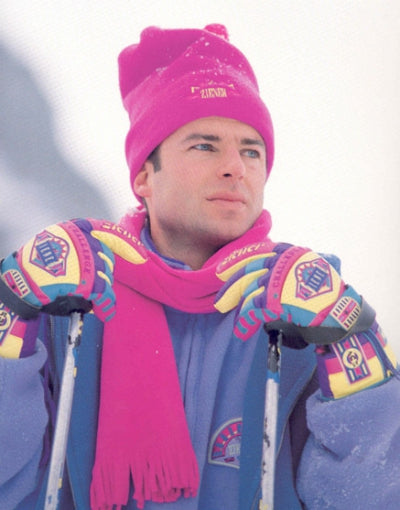 Mann mit pinker Mütze und pinkem Schal in bunter Skibekleidung der 1990er-Jahre