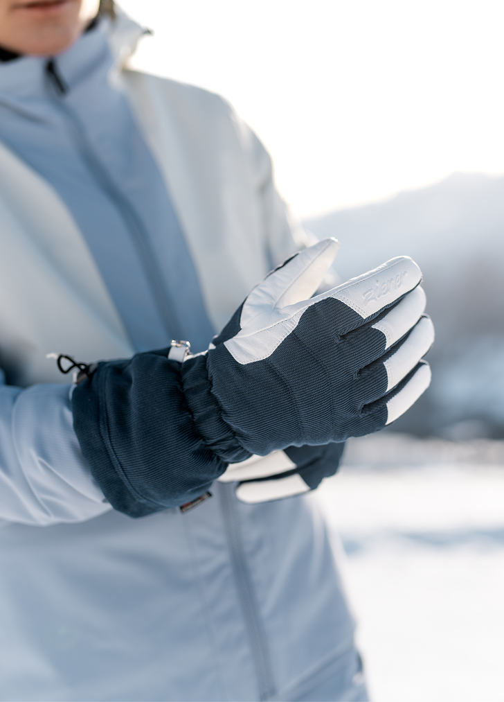 Close-up of navy and white ski gloves worn with a light ski jacket
