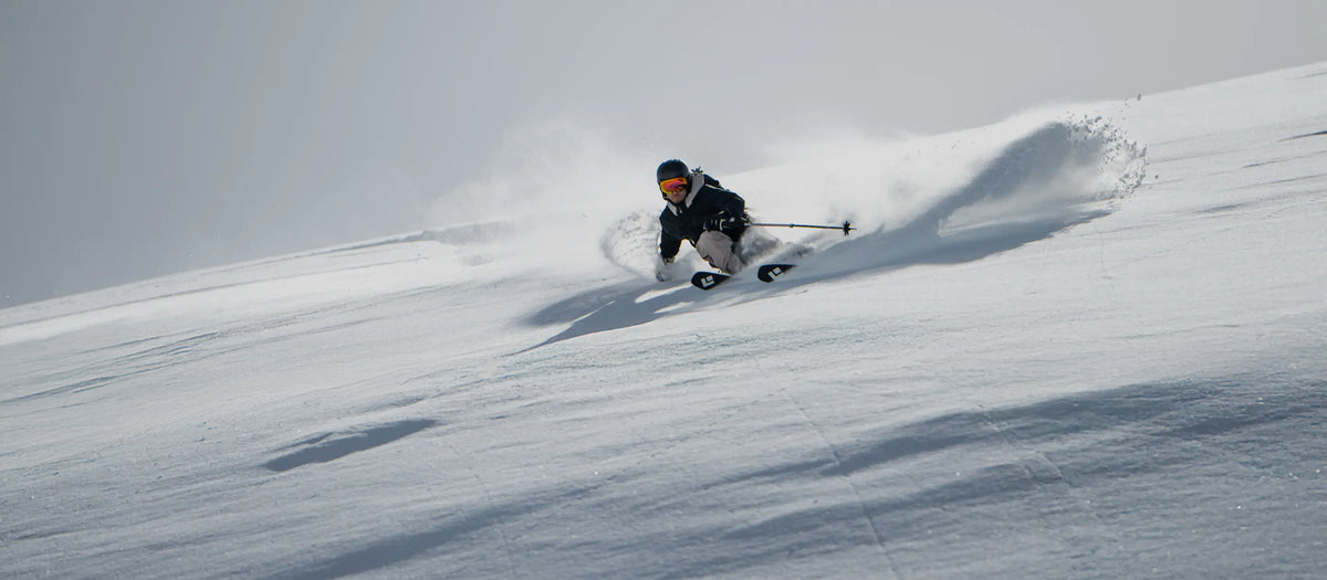 Skifahrer fährt durch Pulverschnee einen weiten Hang hinab